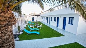 une cour avec des chaises bleues et un palmier dans l'établissement Corralejo Lodge, à Corralejo
