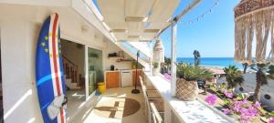 a house with a surfboard on a balcony with the beach at Beach penthouse with rooftopbar and Starlink WiFi, spectacular 180 degrees ocean view in Santa Maria