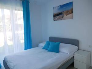 łóżko z niebieskimi poduszkami w pokoju z oknem w obiekcie Wisełka Apartamenty Sea & Lake w Wisełce