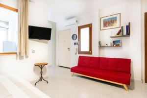 a red couch in a living room with a tv at Bellarosa alloggio Stella Marina in Quartu SantʼElena