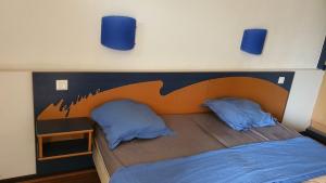 a bed with two blue pillows on top of it at Studio 2 pers à 50 m de la plage in Fleury
