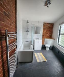 a bathroom with a bath tub and a toilet at Double room with shared facilities in Hitchin