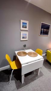 a white table with two yellow chairs in a room at West Kirby Apartment in West Kirby
