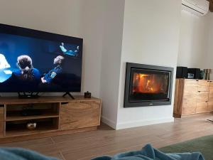 a living room with a flat screen tv and a fireplace at Monte da Lebrinha in Vila Alva