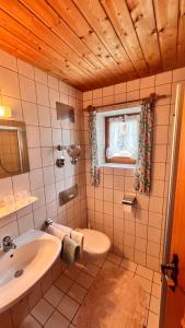 a bathroom with a sink and a toilet and a window at Gästehaus Binderlehen in Schönau am Königssee +13 photos