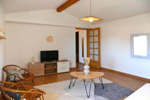 a living room with a tv and a table at Les Roses Trémières - A 1km de la gare garage in Saujon