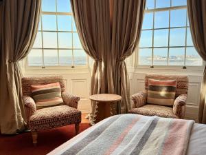a bedroom with two chairs and a bed and windows at Drakes Hotel in Brighton & Hove