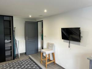 a room with a chair and a television on a wall at T2 Mouguerre aux portes de Bayonne et Biarritz in Mouguerre