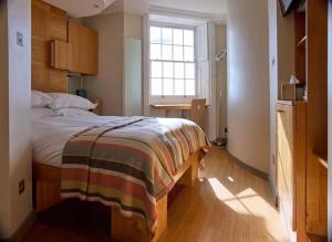 a bedroom with a bed with a striped blanket on it at Drakes Hotel in Brighton & Hove