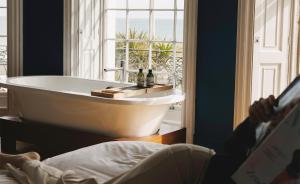 a person reading a book next to a bath tub at Drakes Hotel in Brighton & Hove