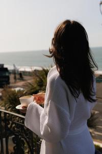 a woman holding a cup of coffee overlooking the beach at Drakes Hotel in Brighton & Hove