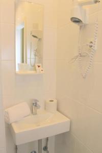 a white bathroom with a sink and a mirror at Hostel S16 in Munich