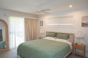 une chambre avec un lit et un ventilateur de plafond dans l'établissement Harper House, à Suffolk Park