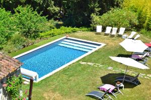 a swimming pool in a yard with chairs and umbrellas at Domaine de la Salutière - Charme & Confort au cœur du Pays Cathare in Lauraguel