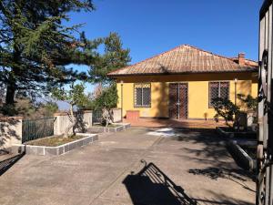 a yellow house with a fence and a driveway at casa la volpe in Linguaglossa