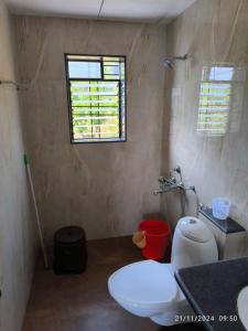 ein Bad mit einem weißen WC und einem Fenster in der Unterkunft Eagle Eye Resort in Mahabaleshwar