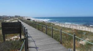 a wooden boardwalk leading to a beach with the ocean at Casa do Bento - Rustic Cozy Loft, Vila do Conde in Fajozes