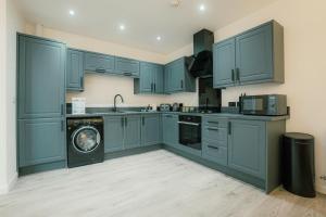 a kitchen with blue cabinets and a washing machine at Hidden Gem in Plymouth