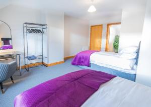 Un dormitorio con dos camas y un escritorio y un espejo. en The Townhouse Ballycastle, en Ballycastle