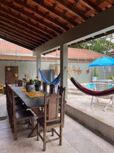 Un patio con mesa y hamacas y una piscina. en Lindo Sobrado Amarelo -próximo a praia, en Mongaguá