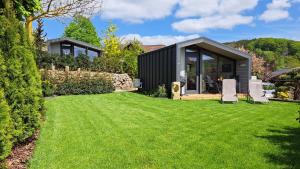a black house with two lawn chairs in a yard at Sauerland Tinyworld in Diemelsee