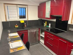 a kitchen with red cabinets and a table with wine glasses at Chez Joselyne in Bezons