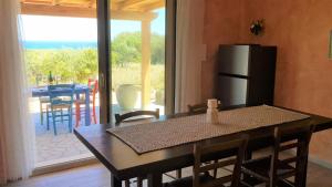 a kitchen with a table with chairs and a refrigerator at Country villa Sant' Elène- Appartamento Mirto in Orosei