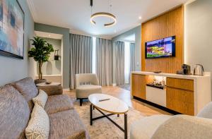 a living room with a couch and a tv at Southern Sun Rosebank, Johannesburg in Johannesburg