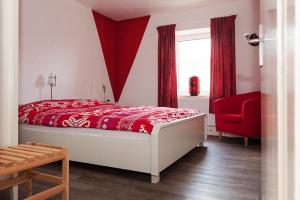 1 dormitorio con cama roja y silla roja en B7 Selfkant, en Selfkant