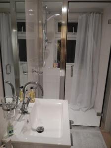 een badkamer met een witte wastafel en een douche bij The Rutlands B&B in Windsor