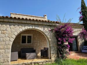 a stone building with an arch with a couch and flowers at Torriciola location villa mûrier in Propriano