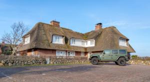 a green jeep parked in front of a thatched house at Sylt-Traum Kampen in Kampen
