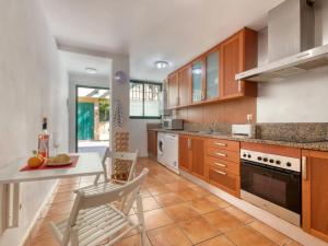 a kitchen with wooden cabinets and a table and chairs at Chalet adosado en Golden Park, Jávea in Jávea