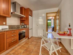 a kitchen with wooden cabinets and a table and chairs at Chalet adosado en Golden Park, Jávea in Jávea