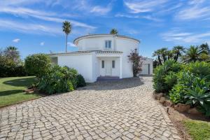 a white house with a cobblestone driveway at Vila Paraiso - Amazing villa in Carvoeiro