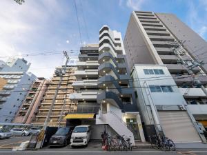 大阪MYB Namba 3BR suite close to Namba Self Check-In的停车场内有车辆停放的高楼