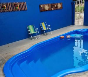 a blue swimming pool with two chairs next to it at Pousada Sorriso da Mata.. in Alter do Chao