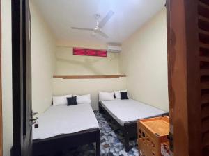 two beds in a small room with a ceiling at Saa in Anuradhapura