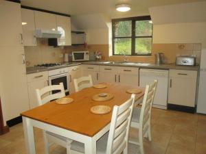 a kitchen with a wooden table and white cabinets at The Dairy in Teignmouth