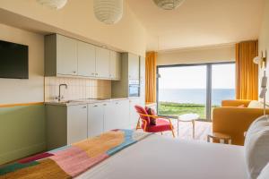 a bedroom with a bed and a kitchen with a view of the ocean at SeaSpace in Newquay
