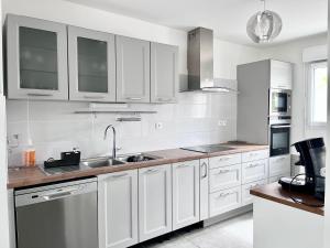 a kitchen with white cabinets and a sink at Happy Villa! in Beauzelle