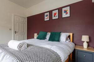 een slaapkamer met een groot bed met groene en witte kussens bij Modern 4-Bed Home Sleeps 6 in Stockton-on-Tees