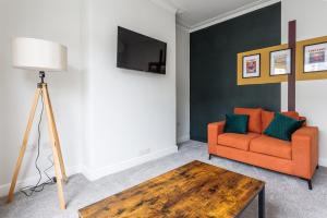 een woonkamer met een oranje bank en een tafel bij Modern 4-Bed Home Sleeps 6 in Stockton-on-Tees