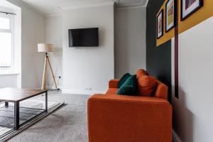 een woonkamer met een oranje stoel en een tafel bij Modern 4-Bed Home Sleeps 6 in Stockton-on-Tees +42 foto's