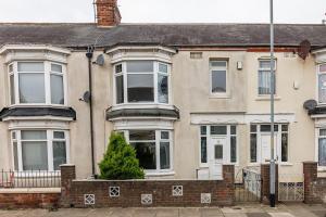 een groot bakstenen huis met een boom ervoor bij Modern 4-Bed Home Sleeps 6 in Stockton-on-Tees