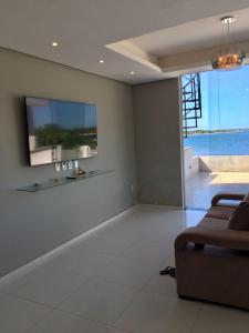 a living room with a couch and a tv on the wall at Apartamento Lagoa do Paraiso - Jericoacoara in Jijoca de Jericoacoara