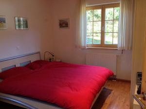 1 cama roja en un dormitorio con ventana en Gorgeous Chalet in Truttli Area of Lauenen, en Lauenen