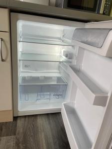 an empty refrigerator with its door open in a kitchen at Gästewohnung 1 Zum Stadtwald Spremberg in Spremberg