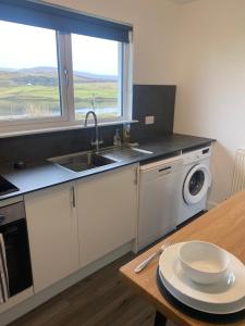 a kitchen with a sink and a washing machine at Almondbank Cottage 8 miles from Portree 2 bedrooms sleeps 3 adults in Skeabost