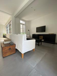 a living room with a white couch and a tv at Casa céntrica con pileta y parrilla in Tandil +30 photos